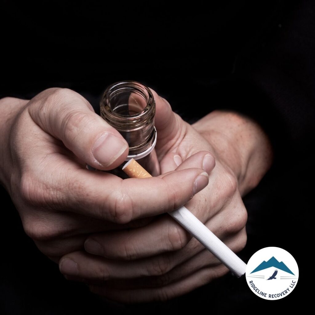 A persons hands holding a cigarette and an empty liquor bottle, symbolizing addiction and the need for treatment.