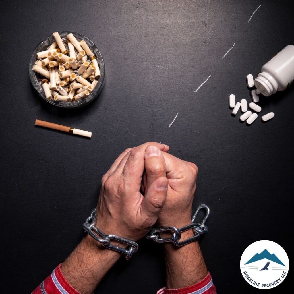 Hands bound by chains with scigarettes, pills, and drug paraphernalia scattered around, symbolizing the grip of addiction and the need for addiction therapy in Columbus.