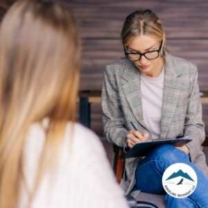 A therapist in glasses and a plaid blazer takes notes while counseling a woman in a recovery session. AA and NA meetings in Columbus, Ohio, offer vital support for individuals overcoming substance abuse.