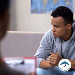 A young man in a gray hoodie sits attentively in a counseling session, deep in thought. Halfway House Columbus Ohio provides a structured environment where individuals receive guidance, peer support, and the tools needed for a successful transition from rehab to independent living.