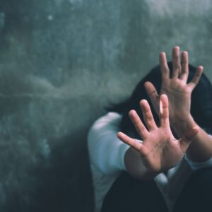 A person sitting against a rough wall, raising their hands in distress, symbolizing the struggles of addiction and the importance of substance abuse group worksheets in the recovery process.