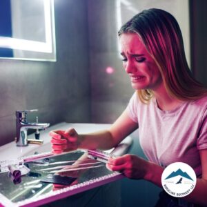 A distressed young woman sits in a bathroom, crying as she prepares to use drugs, emphasizing the urgent need for rehabs in Ohio that take Medicaid to provide accessible addiction treatment and support.