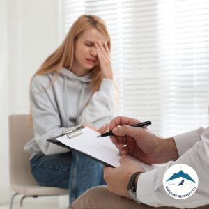 A young woman in distress sits in a therapy session while a professional takes notes, representing the importance of Inpatient Rehab Medicaid in providing accessible addiction treatment in Columbus, Ohio.