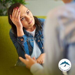 A woman in distress listens attentively during a counseling session, emphasizing the importance of emotional support and structured guidance in Sober Living Columbus Ohio for a successful recovery journey.