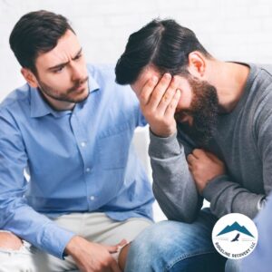 A distressed man receives emotional support from a friend during an Addiction Therapy Near Me session, highlighting the importance of peer encouragement in the recovery process.