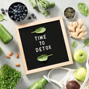 A board with "Time to Detox" written on it, surrounded by fresh greens, fruits, and detox drinks, representing the role of Ambulatory Detox in a safe and natural recovery process.