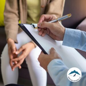 A professional counselor takes notes during a one-on-one session, highlighting the personalized approach of Day Treatment Programs in addiction recovery and mental health support.