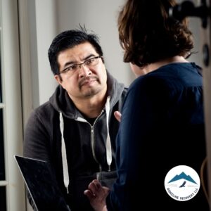 A man attentively listening to a counselor during a therapy session at a Medicaid-covered inpatient drug rehab, focusing on addiction recovery and emotional support.