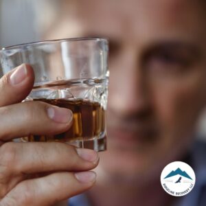 A man intensely staring at a glass of alcohol, symbolizing the struggle with addiction and the path to recovery through PHP Level of Care in Ohio.