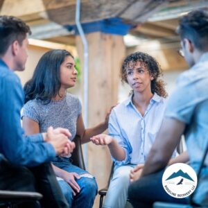 A diverse group of people sits in a circle, engaging in a supportive discussion, representing the power of community in Sober Living Rooms for Rent in Columbus.