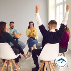 A group of individuals in a supportive addiction recovery session at a drug rehab center in Columbus, Ohio, celebrating progress together.