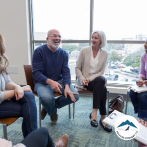 A supportive addiction recovery group in a long-term inpatient rehab near me, engaging in discussion and laughter during therapy.