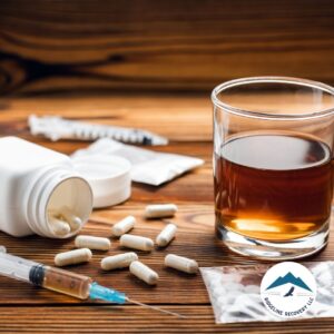 A glass of alcohol sits beside scattered pills, a syringe, and drug packets, highlighting the dangers of substance abuse and the urgent need for a detox from alcohol near me in Columbus, Ohio.