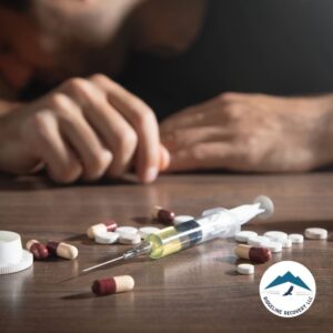 A person struggling with opioid addiction, with scattered pills and a syringe on a table, representing the need for Suboxone addiction treatment in Columbus.