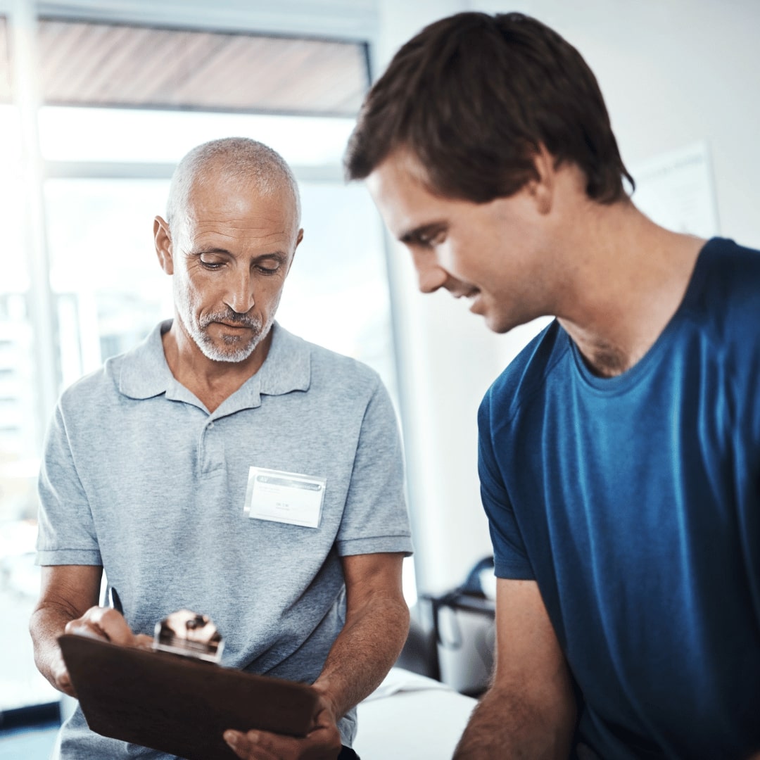 A therapist providing therapeutic behavioral services and day treatment programs, guiding a male patient through a personalized treatment plan in a supportive environment.