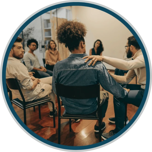 A group counseling session in progress, featuring individuals sitting in a circle, engaged in discussion with a counselor, creating a supportive environment for sharing experiences and fostering recovery at Ridgeline Recovery.