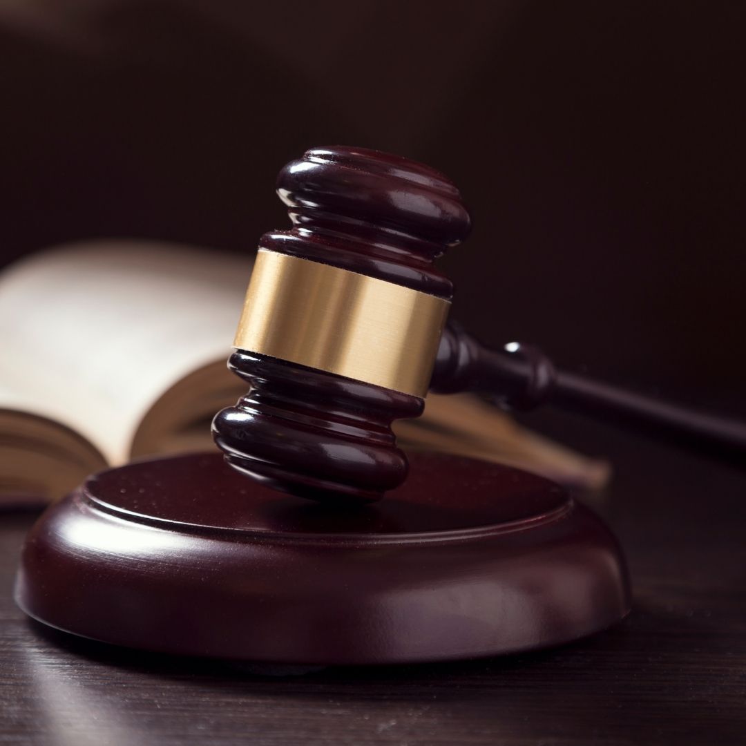 A judge’s gavel resting on a wooden base with an open law book in the background, representing the legal authority behind court mandated drug treatment for addiction recovery.