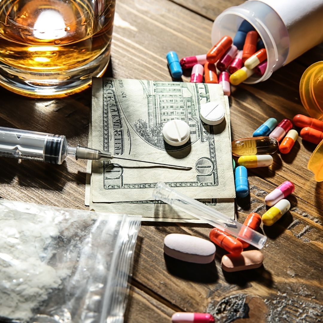 A disturbing scene of addiction featuring pills, a syringe, powder, cash, and a glass of alcohol, symbolizing the need for a Drug and Alcohol Assessment Columbus Ohio to help individuals seek professional recovery solutions.