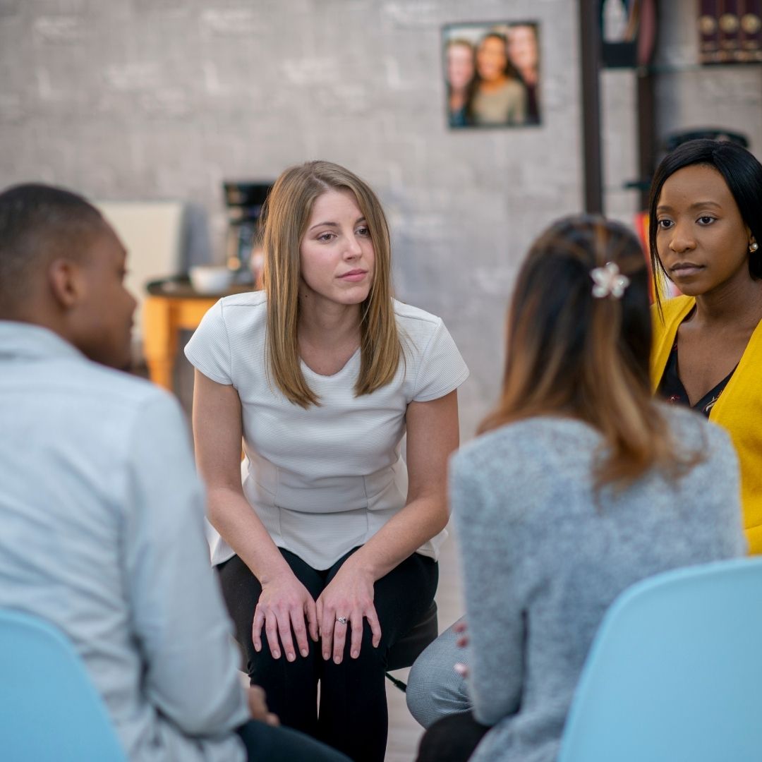 A small group of individuals sits in a circle, engaged in a supportive discussion in a welcoming sober living environment. A counselor attentively listens, reinforcing the sense of community in Sober Living Rooms for Rent in Ohio.