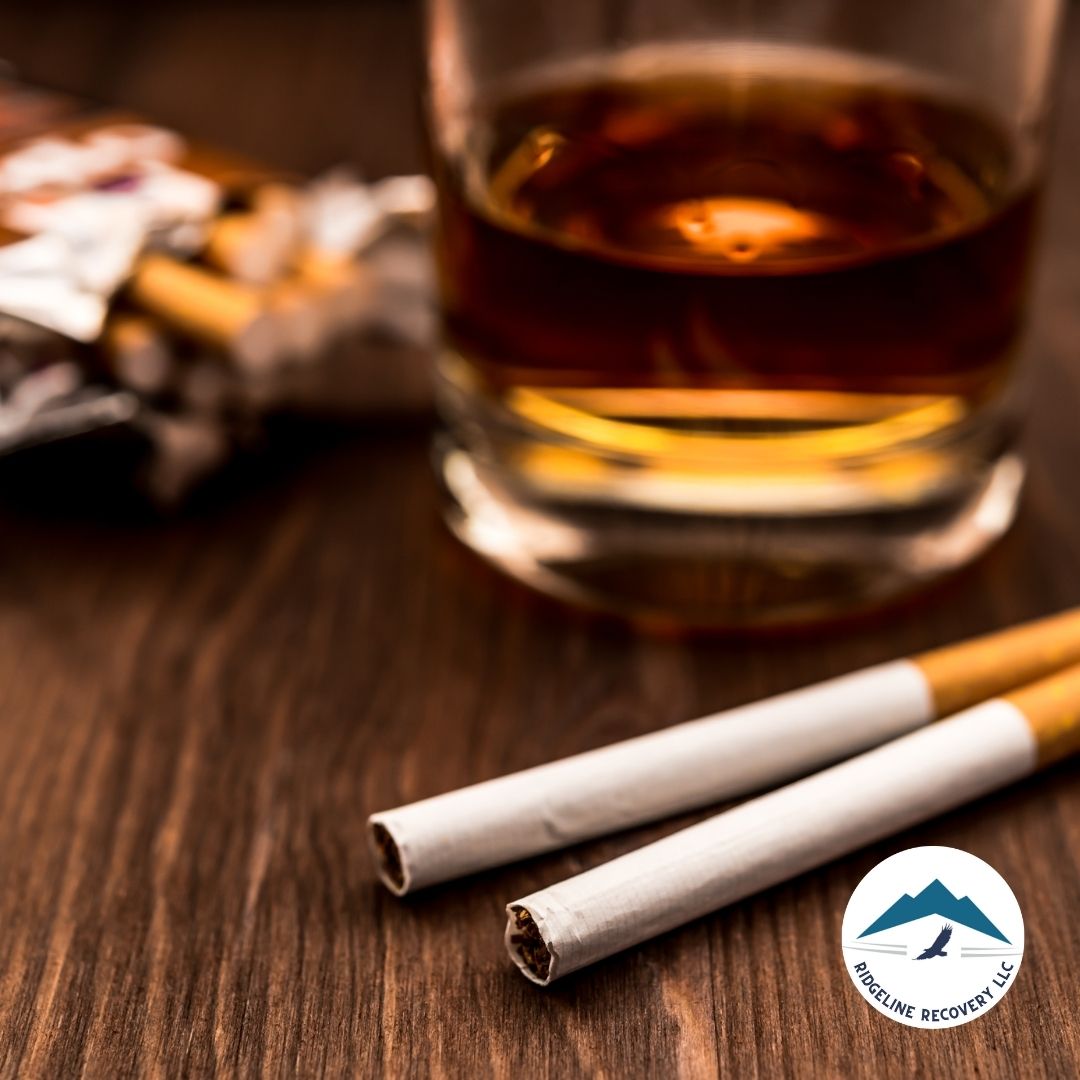 A close-up of a glass of alcohol and cigarettes on a wooden table, representing substance use and the need for Registered Nurse Services in addiction recovery to provide medical care, detox assistance, and support for long-term healing.