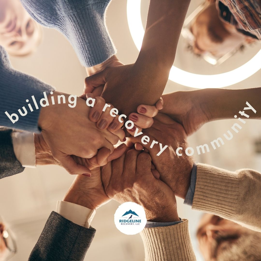 A group of diverse individuals join hands together in a circle, symbolizing unity and support. Text reads "building a recovery community" with the Ridgeline Recovery LLC logo at the center.