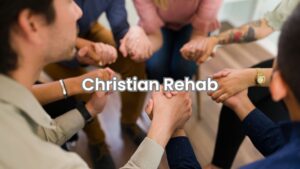 A group of individuals participating in prayer during a Christian rehab session in Columbus.