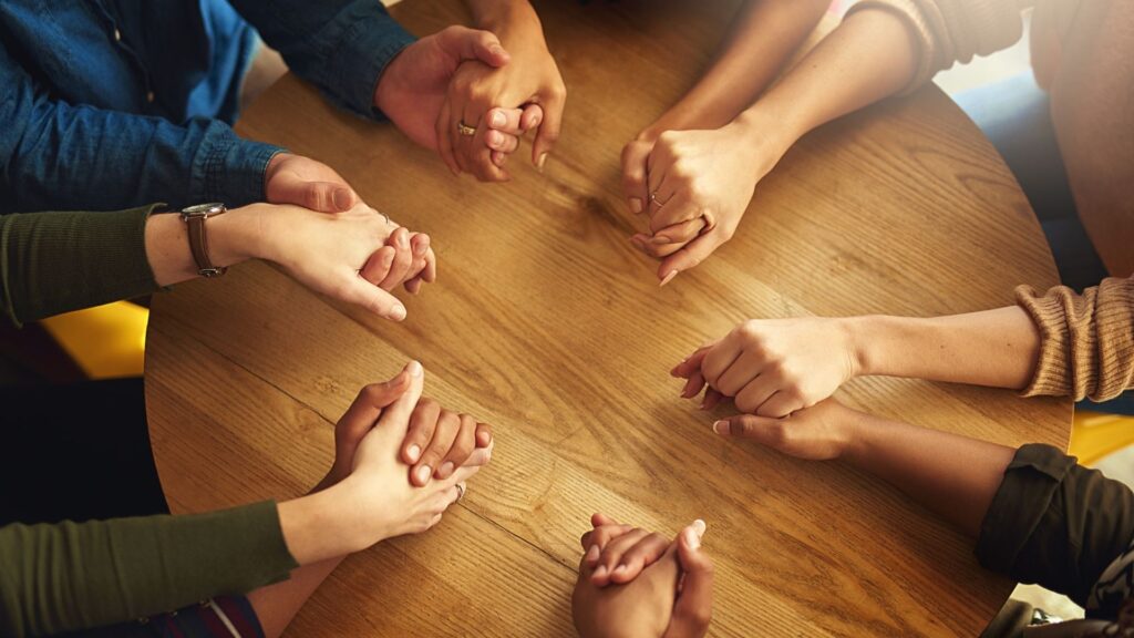 Hands holding together during a faith-based recovery group session in Columbus.