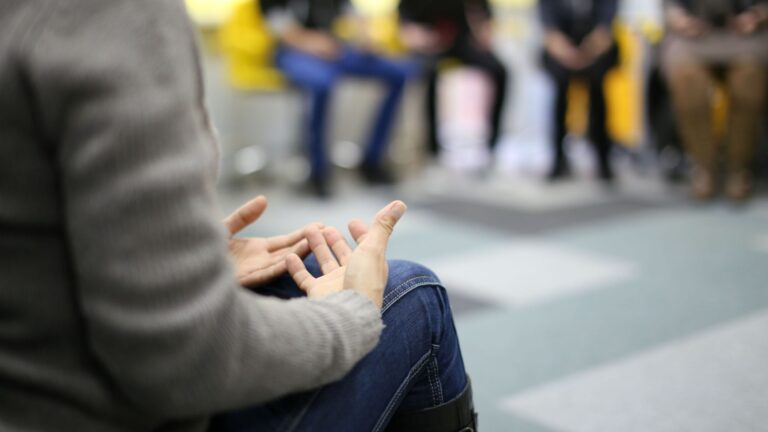 A diverse group of individuals in addiction therapy sitting in a circle, actively engaging in discussion.