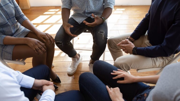 A recovery group in a supportive gesture during an addiction treatment session.